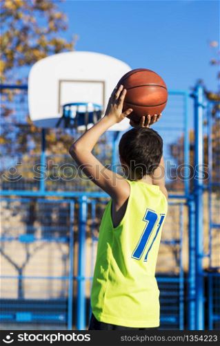 teenager throwing a basketball into the hoop from behind