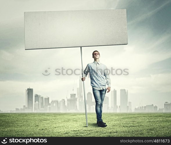 Teenager with banner. Young man against city background holding blank banner. Place for text