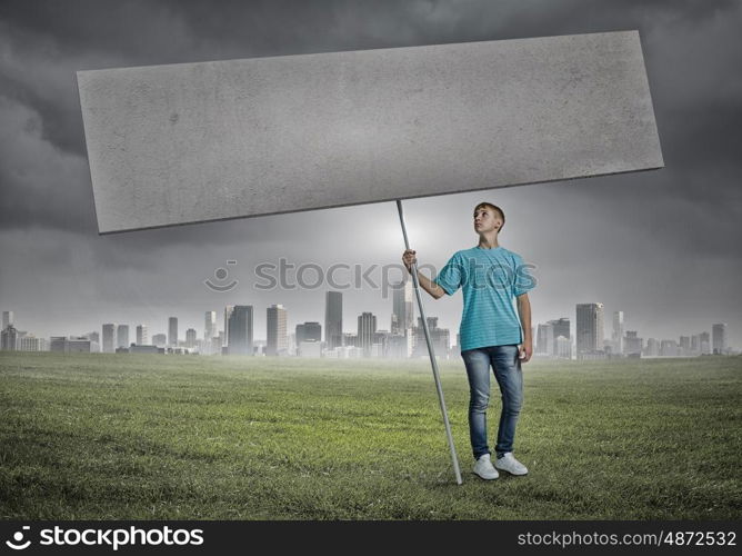 Teenager with banner. Young man against city background holding blank banner. Place for text