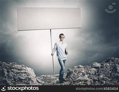 Teenager with banner. Young man in glasses holding blank banner. Place for text