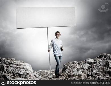 Teenager with banner. Young man in glasses holding blank banner. Place for text