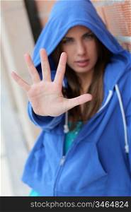 Teenager with blue sweater showing hand to camera