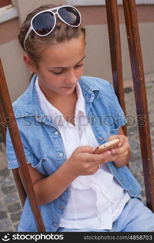 Teenager with gadget sitting on the swings. Teenager with gadgets