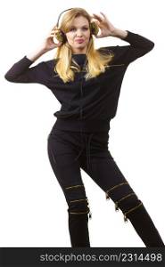 Teenager young grunge woman wearing black and listening to music on headphones with spikes, having fun dancing.. Teenage woman wearing headphones