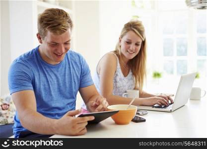 Teenagers Having Breakfast Using Laptop And Tablet Computer