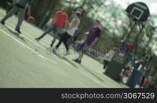 Teenagers playing basketball in a city park. Blured with empty surface in a front.