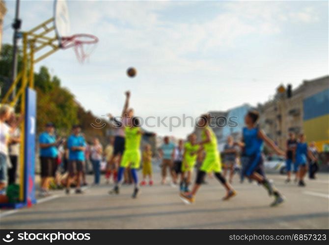 Teenagers playing basketball on the street. Lens blur