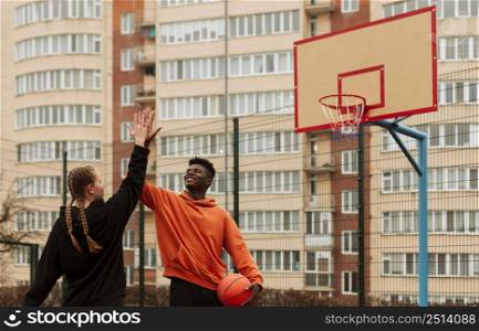 teenagers playing basketball outdoors