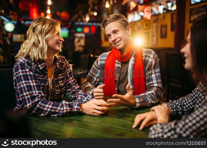Teenagers sitting at the table in sports bar. Football fans, game tv broadcasting, young friends leisures in pub. Teenagers sitting at the table in sports bar