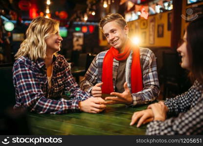 Teenagers sitting at the table in sports bar. Football fans, game tv broadcasting, young friends leisures in pub. Teenagers sitting at the table in sports bar