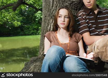 Teenagers sitting by a tree