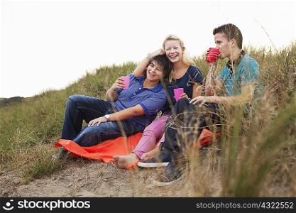 Teenagers sitting on bin bag, having drink