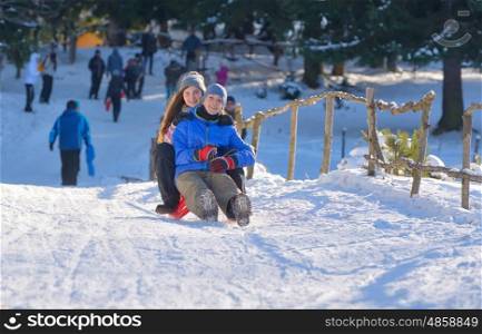teenagers slide downhill in wintertime