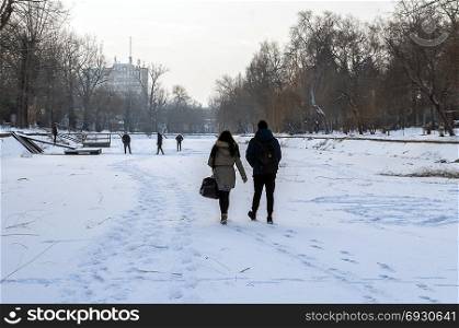 Teenagers walking on a frozen river. Real people. From behind. Rear view.