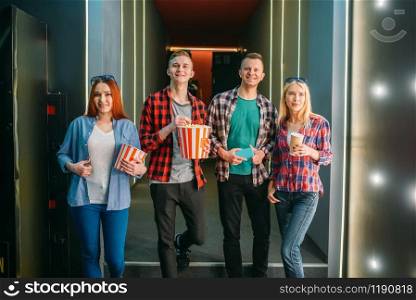 Teenagers with popcorn poses in cinema hall before the screening. Male and female youth in movie theater
