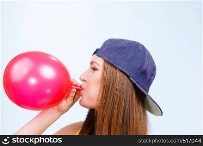 Teens and parties. Preparation for celebration. Trendy teenage girl blowing red balloon. Young beauty woman prepare accessories for party.. Teen girl blowing red balloon.