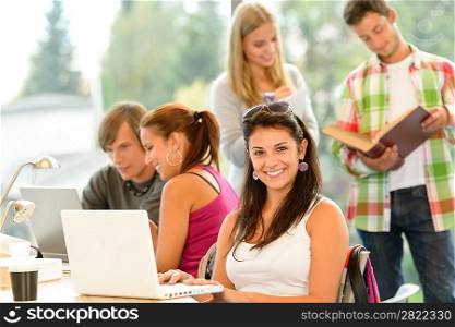 Teens studying in high-school library young pupils smiling laptop book