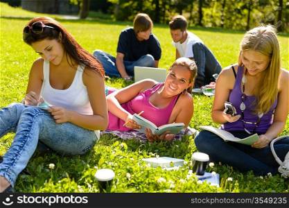 Teens studying in park reading book students happy campus research