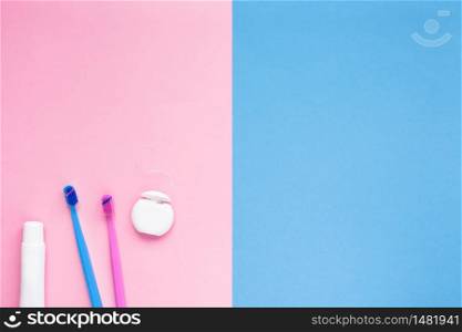 Teeth hygiene and oral dental care products on color pink and blue background with copy space. Blank tube of toothpaste and brushes. Flat lay, top view composition, mockup. Morning concept