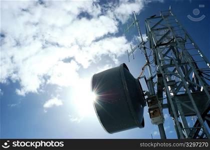 Telecommunication tower in back-light against a cloudy blue sky