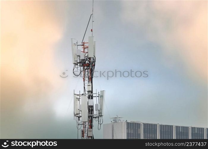 Telecommunication tower near building. Antenna. Radio and satellite pole on gray sky. Communication technology. Telecommunication industry. Mobile or telecom 4g network. Telecommunication industry.