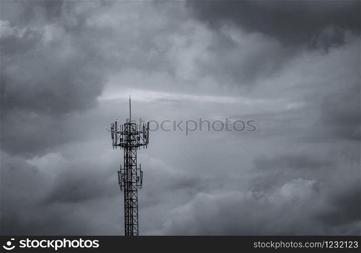 Telecommunication tower with dark sky and white clouds background. Antenna on blue sky. Radio and satellite pole. Communication technology. Telecommunication industry. Mobile or telecom 4g network.