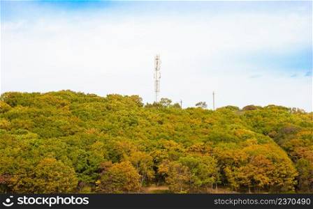 Telecommunications antenna tower or mobile station receiver antenna tower with a coating on the background of mountains and forests.