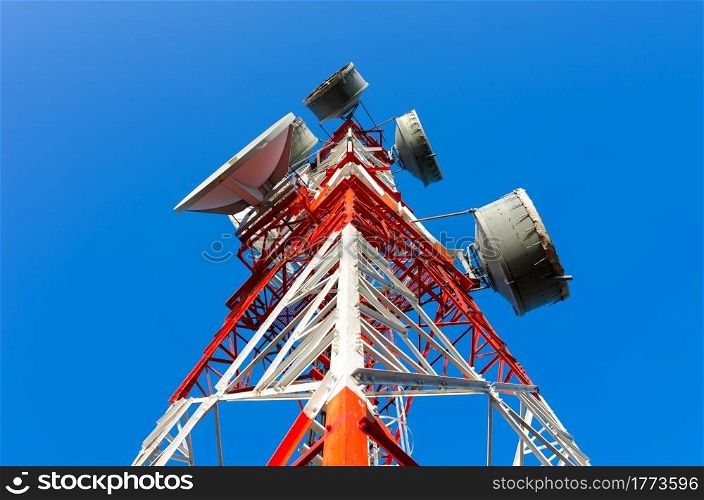 Telecommunications tower, painted white and red in a day of clear blue sky.. Telecommunication tower