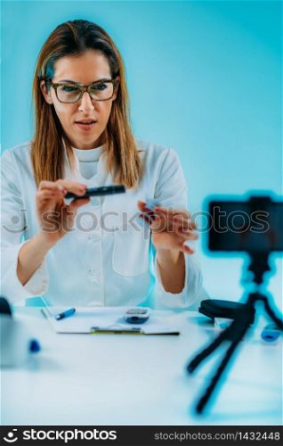 Telehealth ? Medical doctor recording video instructions for patient and demonstrating how to use blood sugar lancet