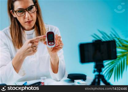 Telehealth ? Medical doctor recording video instructions for patient and demonstrating how to measure blood sugar