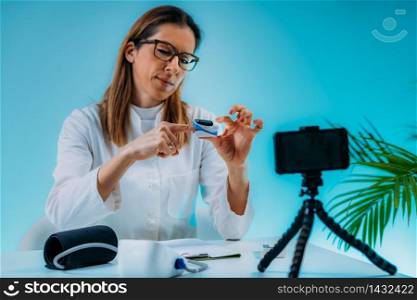 Telehealth ? Medical doctor recording video instructions for patient and demonstrating how to use the oximeter