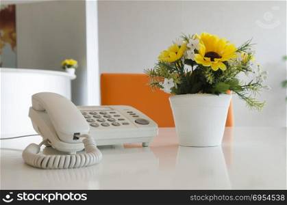 telephone and flower in vase on desk