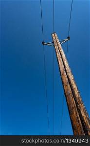 Telephone pole with wires for communication on blue sky. Vertical photo. Telephone pole with wires for communication on blue sky