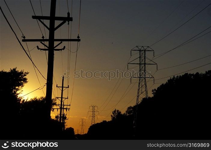 Telephone Poles and Transmission Towers Backlit Against a Dark Sky