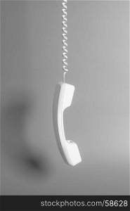 Telephone receiver and cord on gray background.