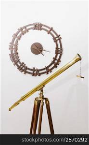 Telescope on a tripod with a clock on a wall