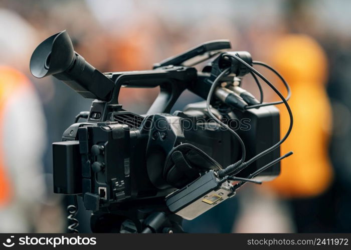 Television camera at the public protest, street demonstrations, blurred people in the background. Television camera at the public protest, street demonstrations