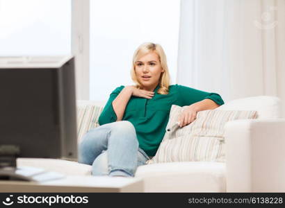 television, leisure and people concept - smiling woman sitting on couch with remote control and watching tv at home