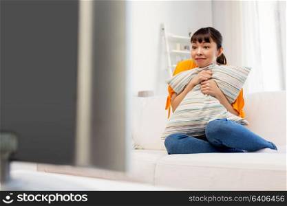 television, leisure and people concept - stunned asian woman watching tv at home and having fun. stunned asian woman with watching tv at home