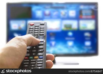 Television remote control changes channels thumb on the blue TV screen