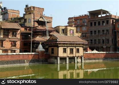 Temple and buildings near green pond in Patan, Nepal