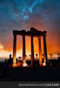 Temple of Apollo in Side against dramatic sky. Lighted columns. Silhouettes of people. Architectural heritage. A popular tourist destination. One of the main attractions of Turkey. Temple of Apollo in Side against dramatic sky