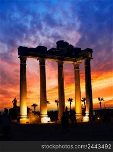 Temple of the Apollo in Side against dramatic sunset sky. Lighted columns. Silhouettes of people. Architectural heritage. A popular tourist destination. One of the main attractions of Turkey. Temple of the Apollo in Side against dramatic sunset sky