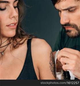 Temporary tattoo. Professional make-up artist applying temporary tattoo sticker to model’s arm