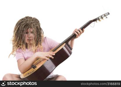 Ten year old girl with rasta wig seriously working on her guitar