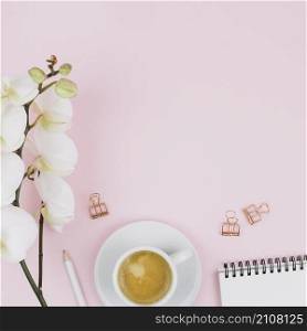 tender beautiful white orchid flower pencil coffee cup spiral notepad bulldog paper clip against pink background