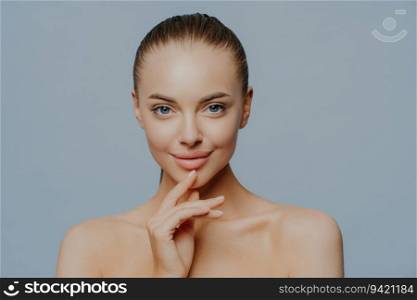 Tender woman, pure skin. Magnetic look, beautiful and attractive. Shirtless against blue background. Enjoying after spa procedures. Beauty care.