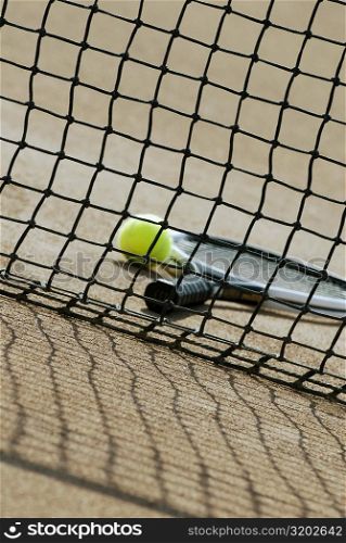 Tennis ball and a tennis racket behind a tennis net