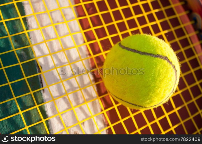 Tennis ball and racket. Yellow tennis nets. Behind the tennis courts.
