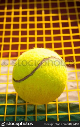 Tennis ball and racket. Yellow tennis nets. Behind the tennis courts.